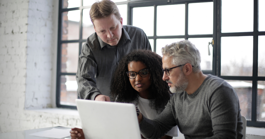 equipe de dois homens e uma mulher em frente a um computador