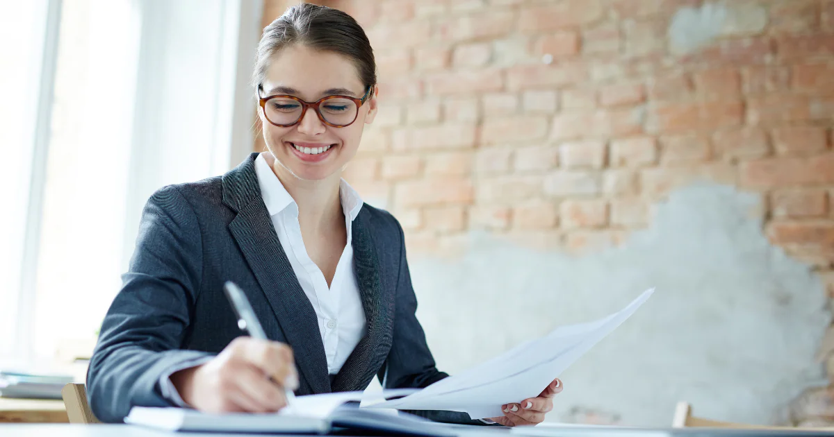Mulher executiva em uma mesa escrevendo e sorrindo