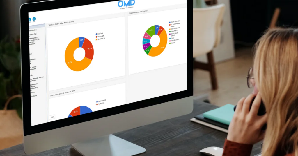 mulher trabalhando em frente ao computador com telefone