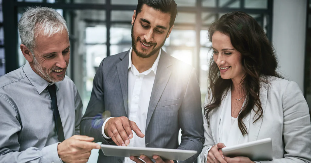 equipe de três pessoas conversando e visualizando uma tela